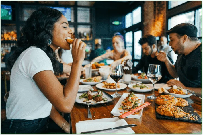 People eating at a big table, filled with various food options