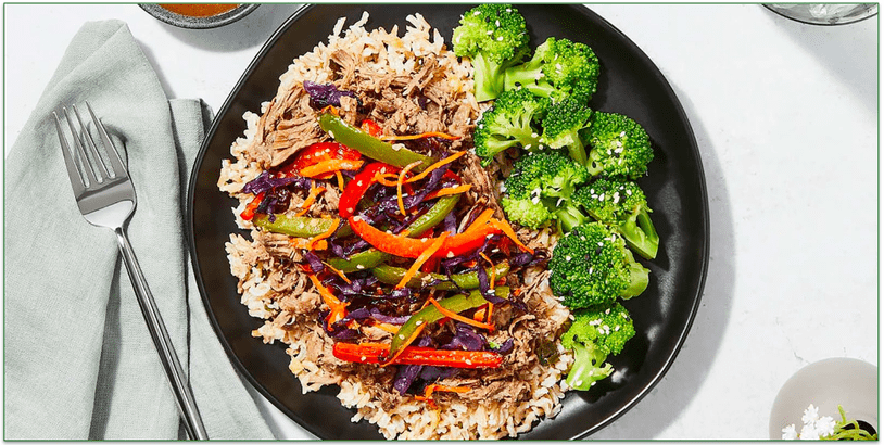 A plate of beef on rice with broccoli and stir-fried vegetables