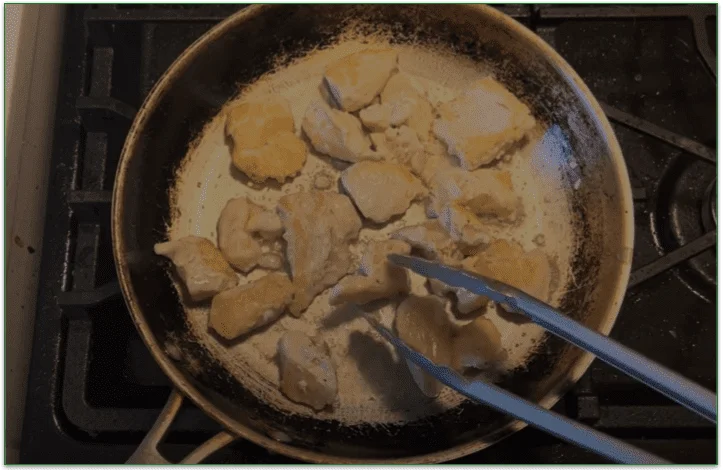 Image of chopped chicken being turned in a pan on the stove