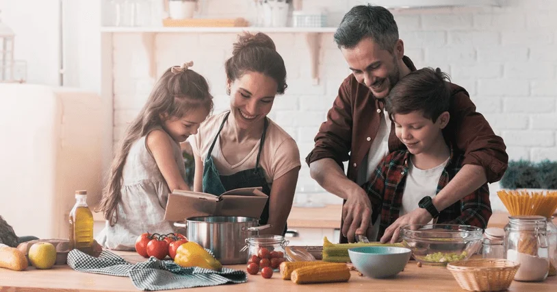 A family of four preparing a meal together in a bright kitchen.