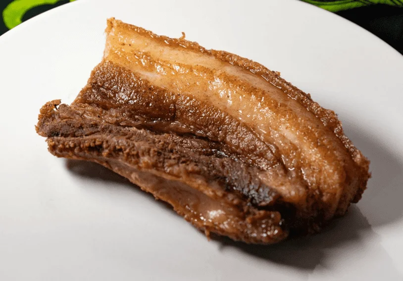 A single crispy cooked piece of pork belly on a plate