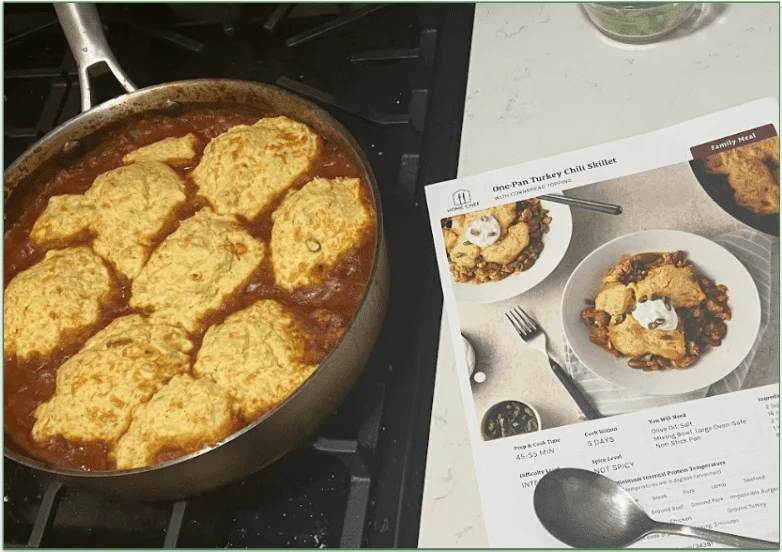 Photo of Home Chef's One-Pan Turkey Chili Skillet being cooked in a skillet next to the Home Chef recipe card