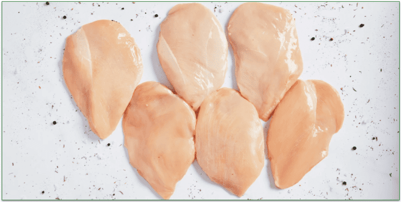 six raw chicken breasts on a marble table